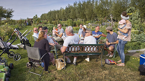 Groep mensen buiten tussen de volkstuintjes
